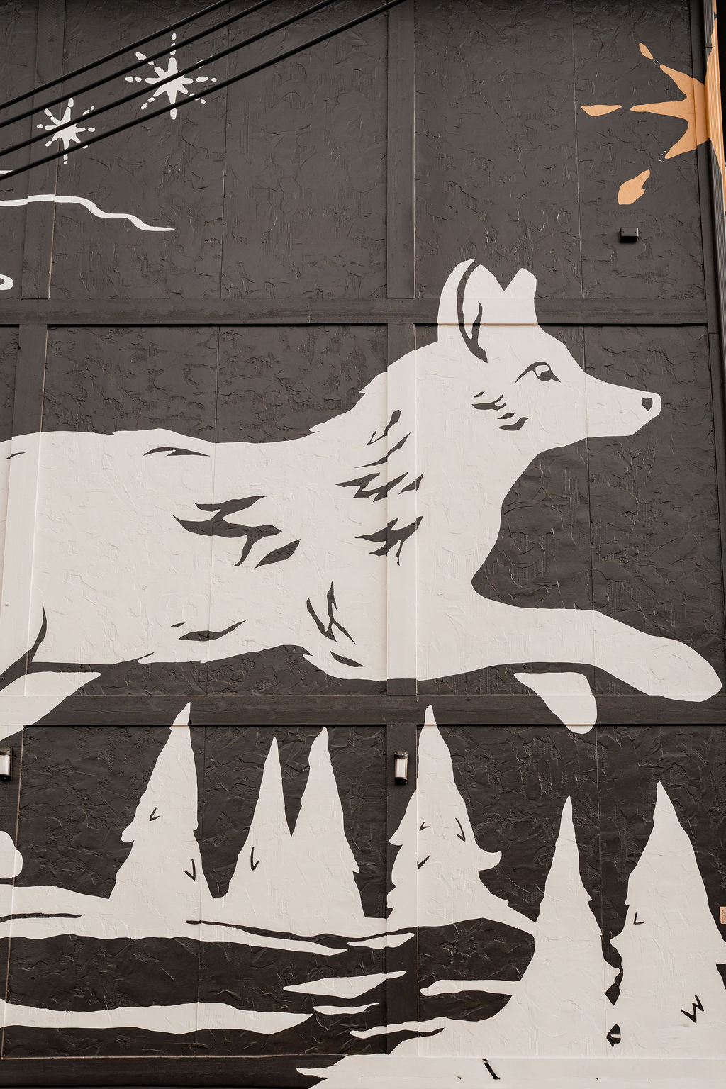 The Outrider Hotel exterior wolf mural with pine trees painted on dark building facade