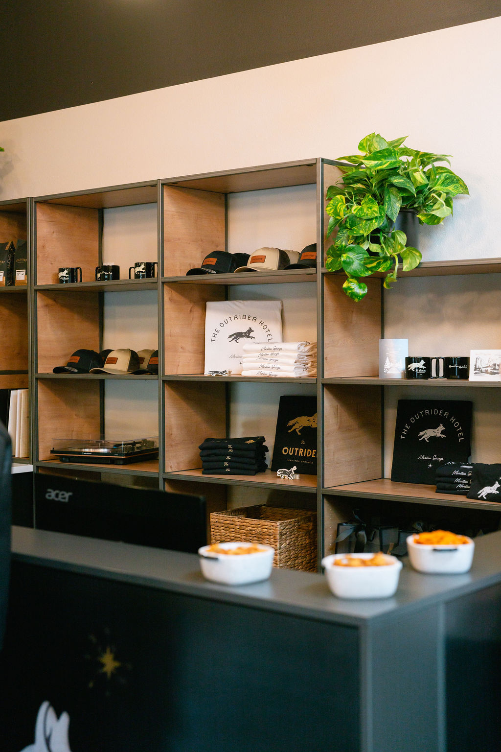 The Outrider Hotel front desk with branded merchandise shelves displaying hats, shirts, and mugs