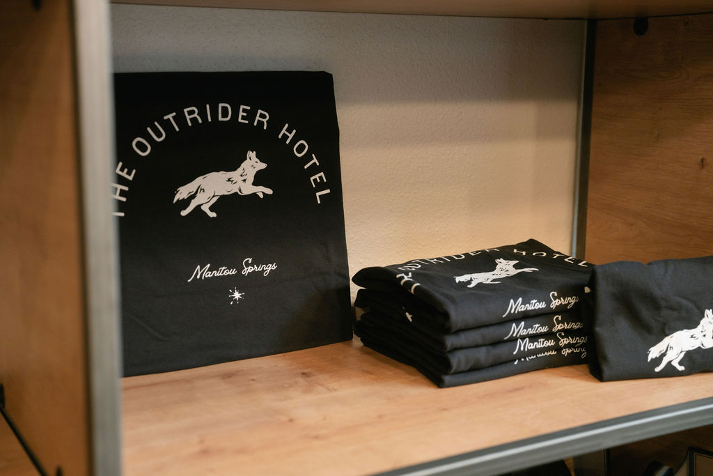 The Outrider Hotel branded t-shirts and tote bags displayed on lobby shelf
