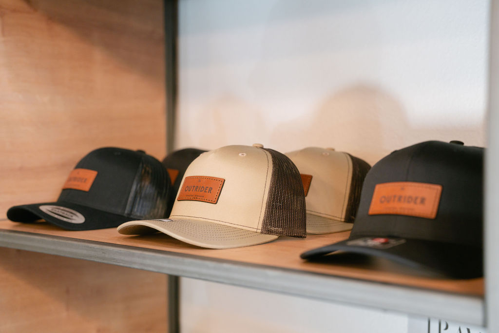 Outrider Hotel branded trucker hats with leather patch displayed on lobby shelf