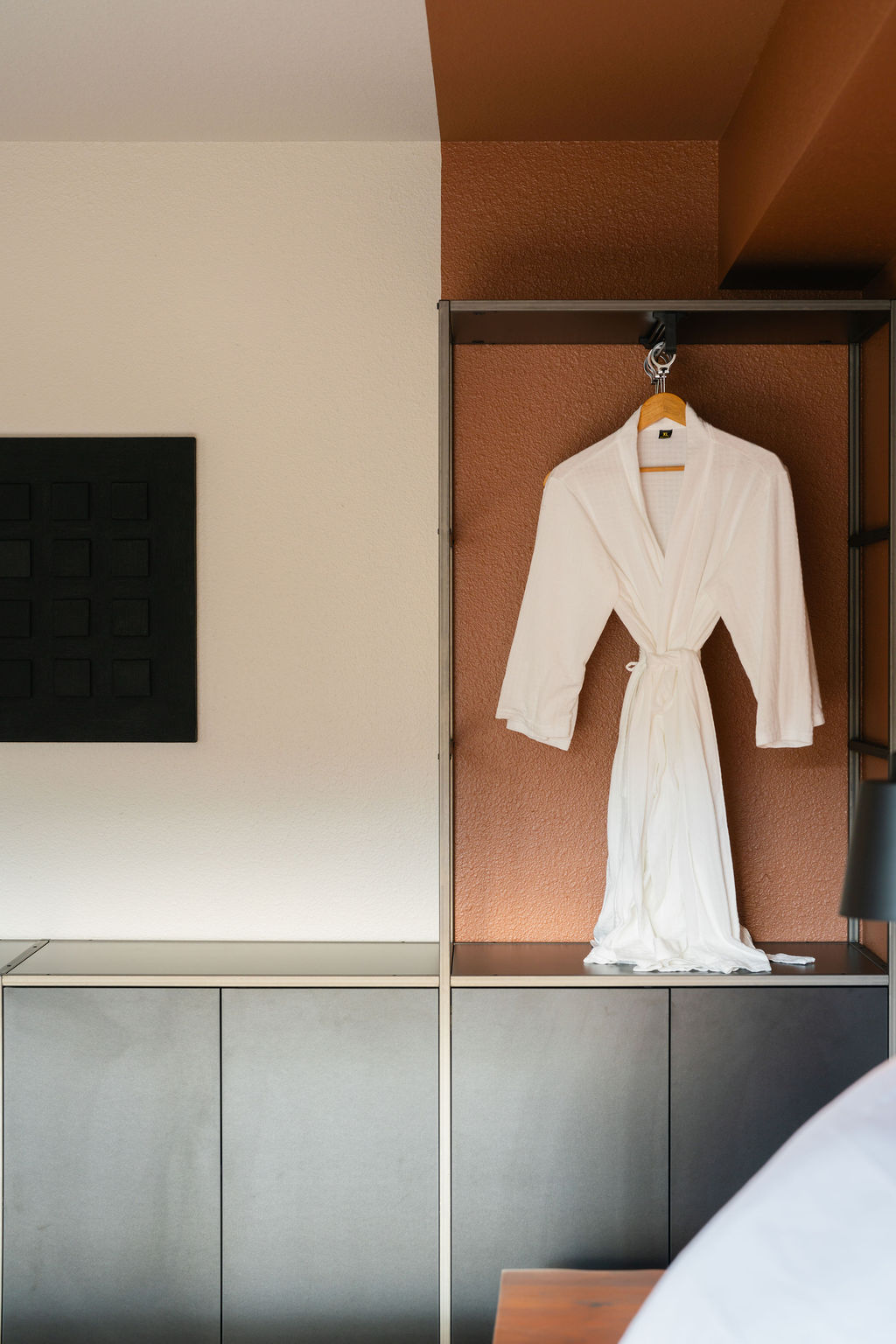 White robe in Outrider Hotel room with dark geometric artwork on wall