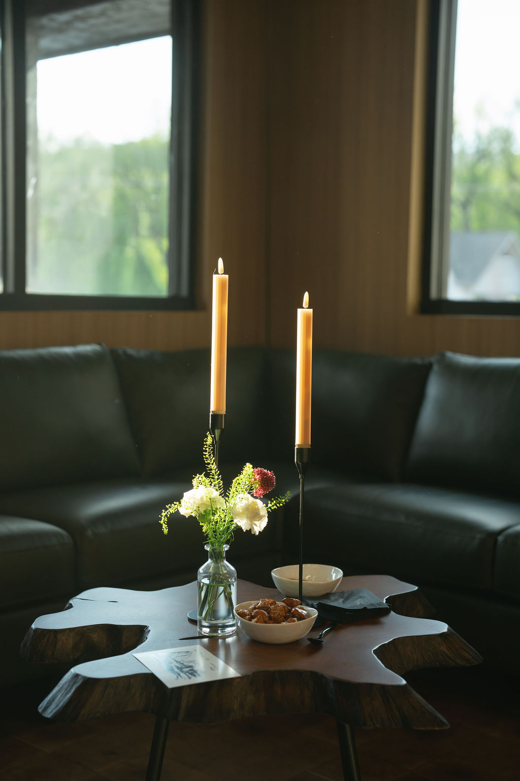 The Outrider Hotel lounge with curved leather sofa, beeswax candles, and live-edge coffee table