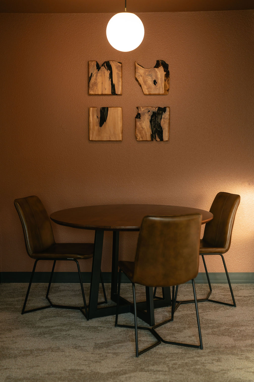 Suite dining area at The Outrider Hotel with round walnut table, leather chairs, and local wood art