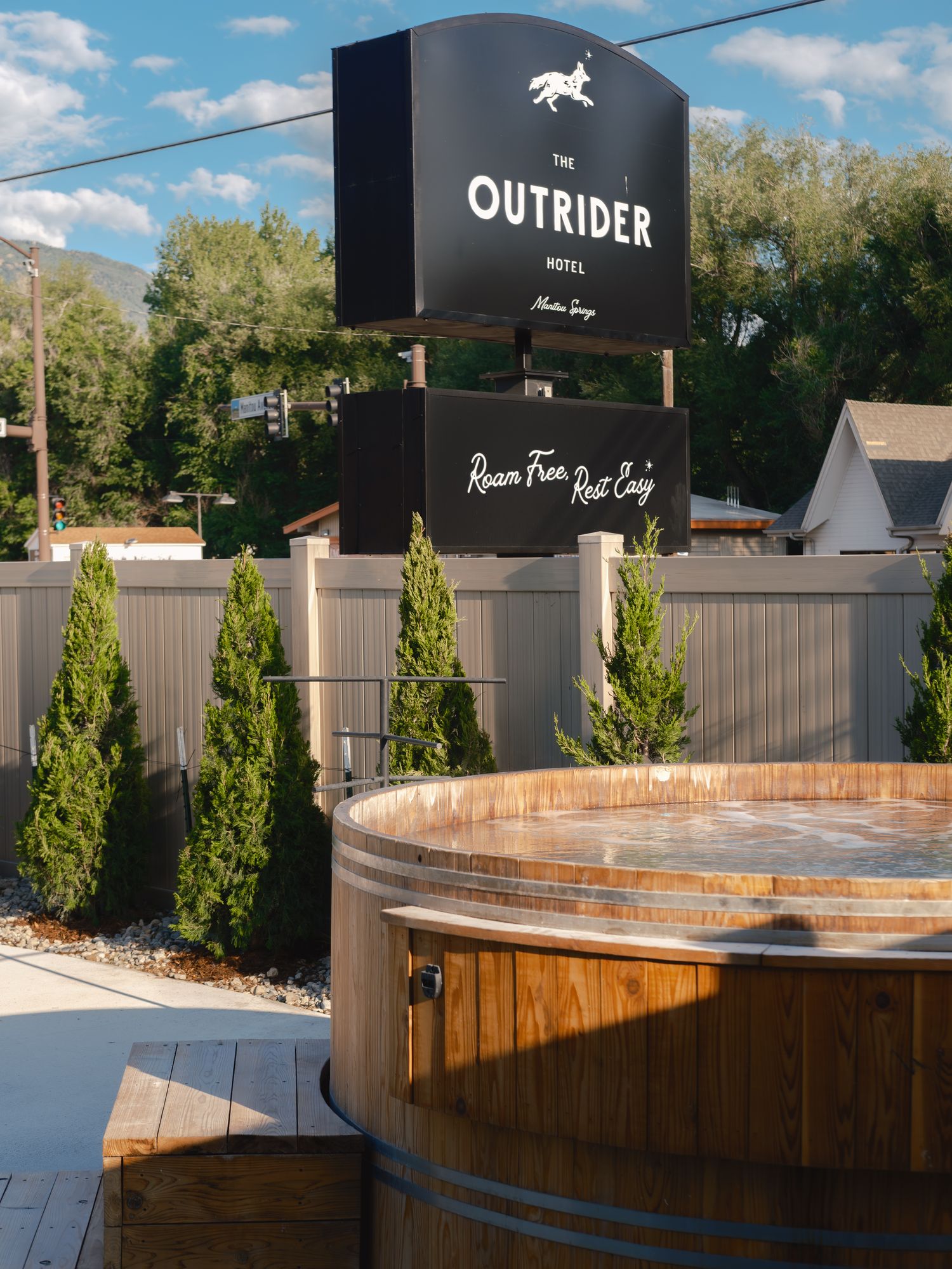 Steaming cedar hot tub in front of The Outrider Hotel sign in Manitou Springs