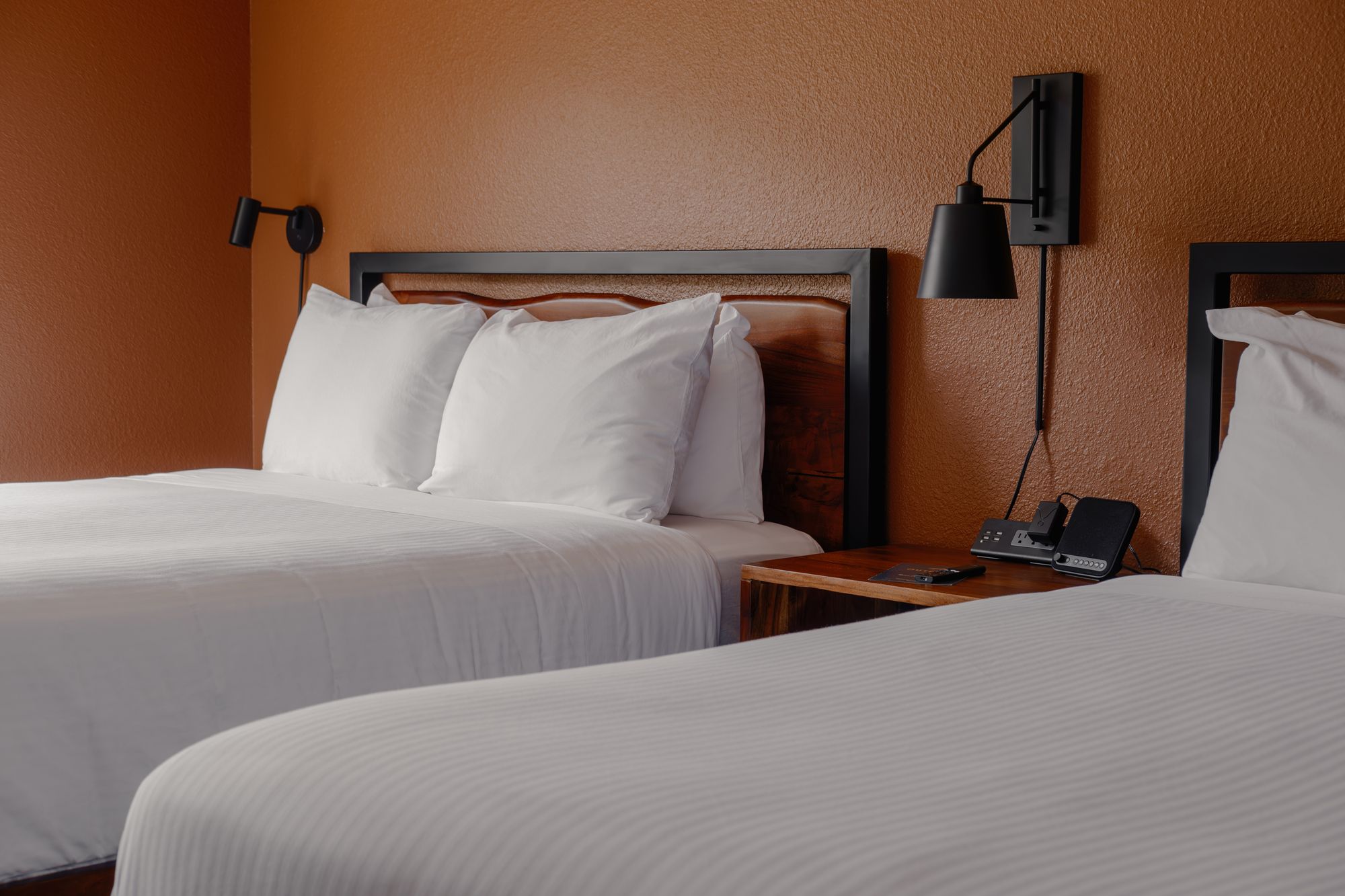 Bedside sconces and white queen bedding in a Classic Double Queen room at The Outrider Hotel, Manitou Springs