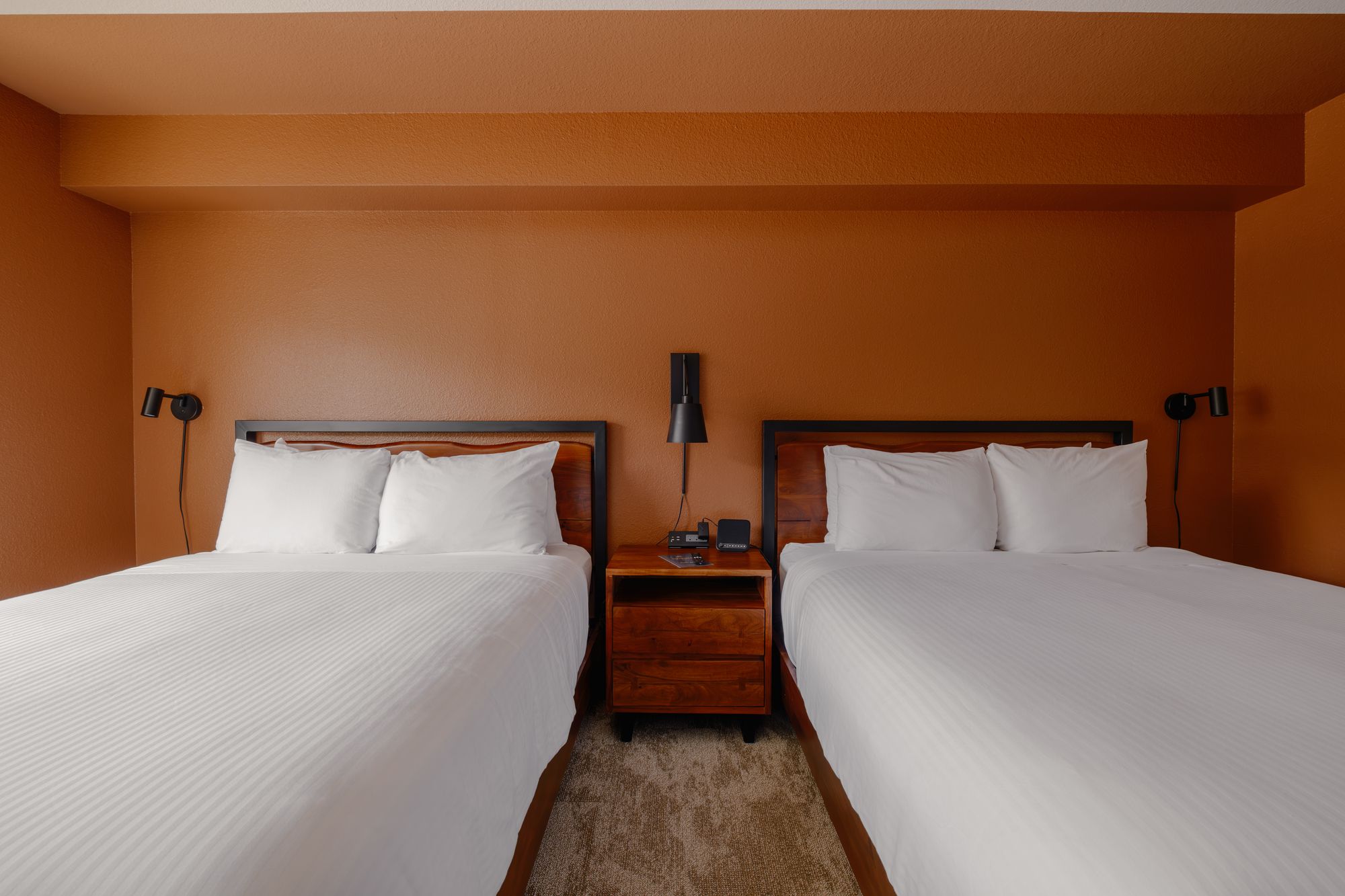 Two queen beds with live-edge wood headboards and a shared nightstand in a Classic Double Queen room at The Outrider Hotel