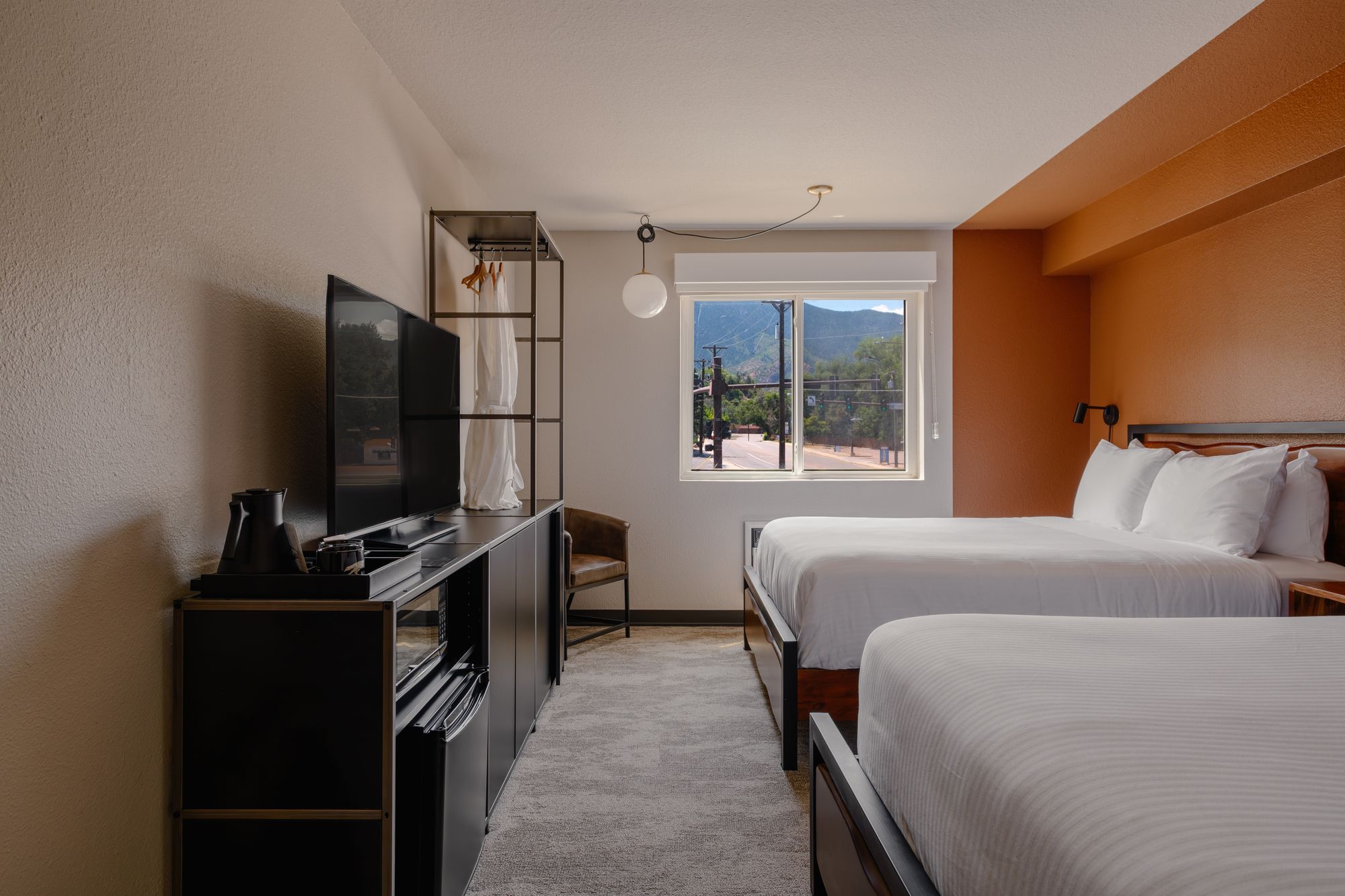 Classic Double Queen room with two queen beds and a mountain-view window at The Outrider Hotel