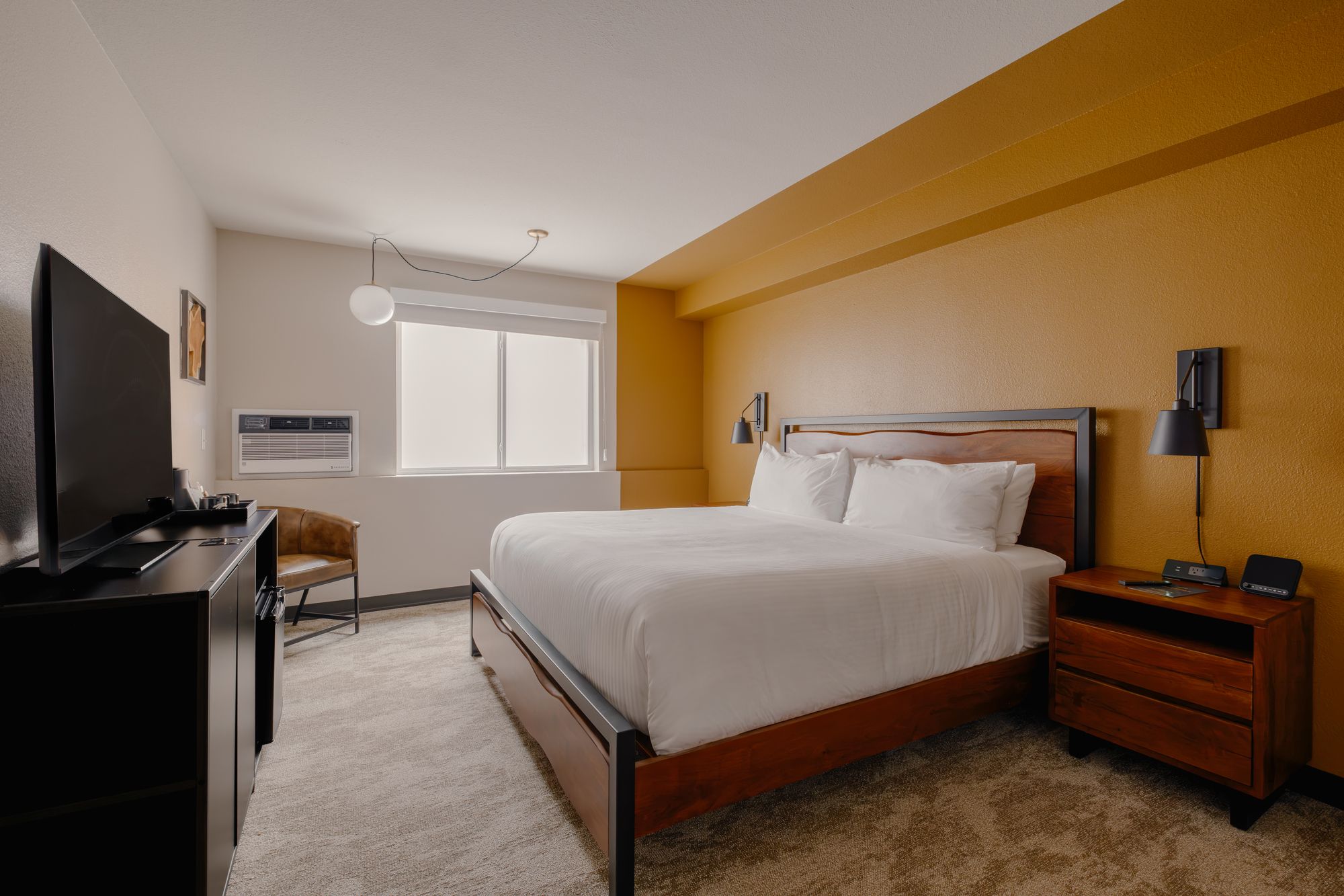 Classic King room with a king bed and mustard accent wall at The Outrider Hotel