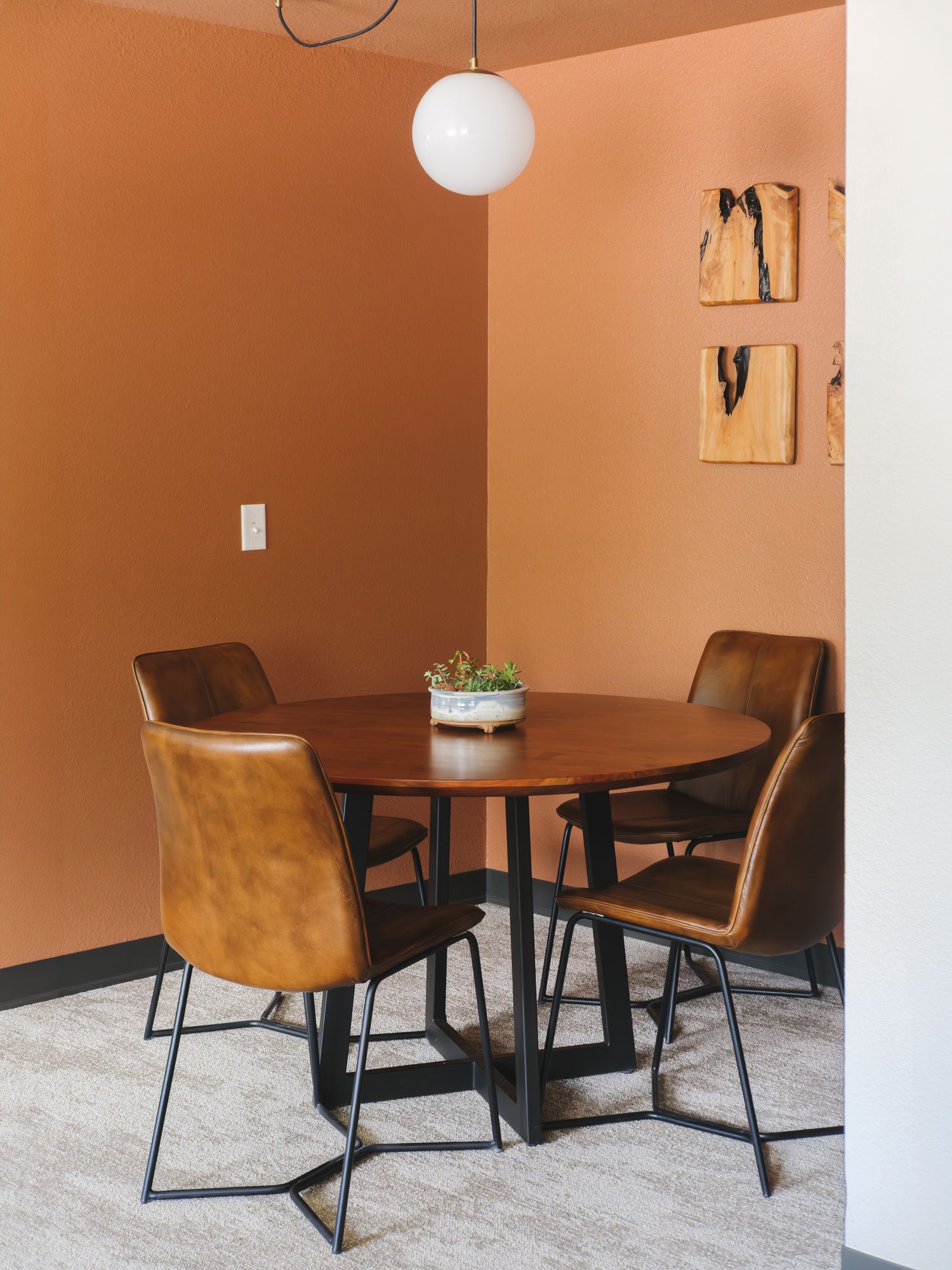 Round dining table with leather chairs and wood wall art in the dining nook of a Grand King Suite at The Outrider Hotel