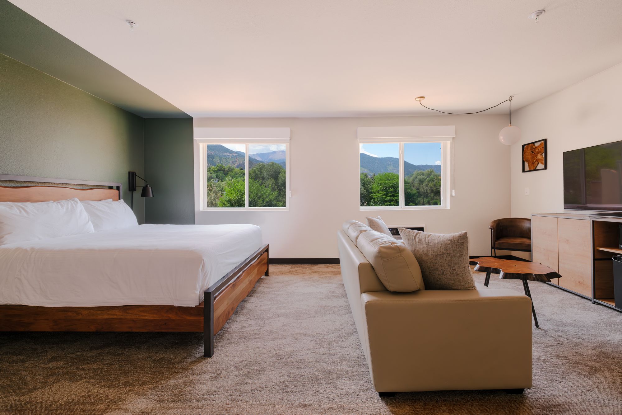 Grand King Suite with a king bed, cream sofa, and two windows framing the mountains above Manitou Springs