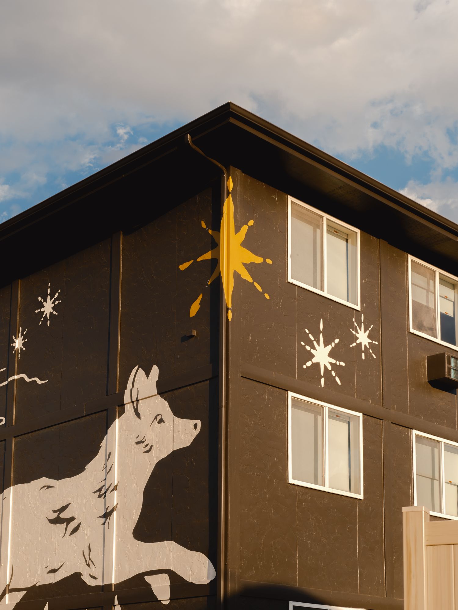 Corner of The Outrider Hotel with painted wolf and gold star mural against a blue Colorado sky