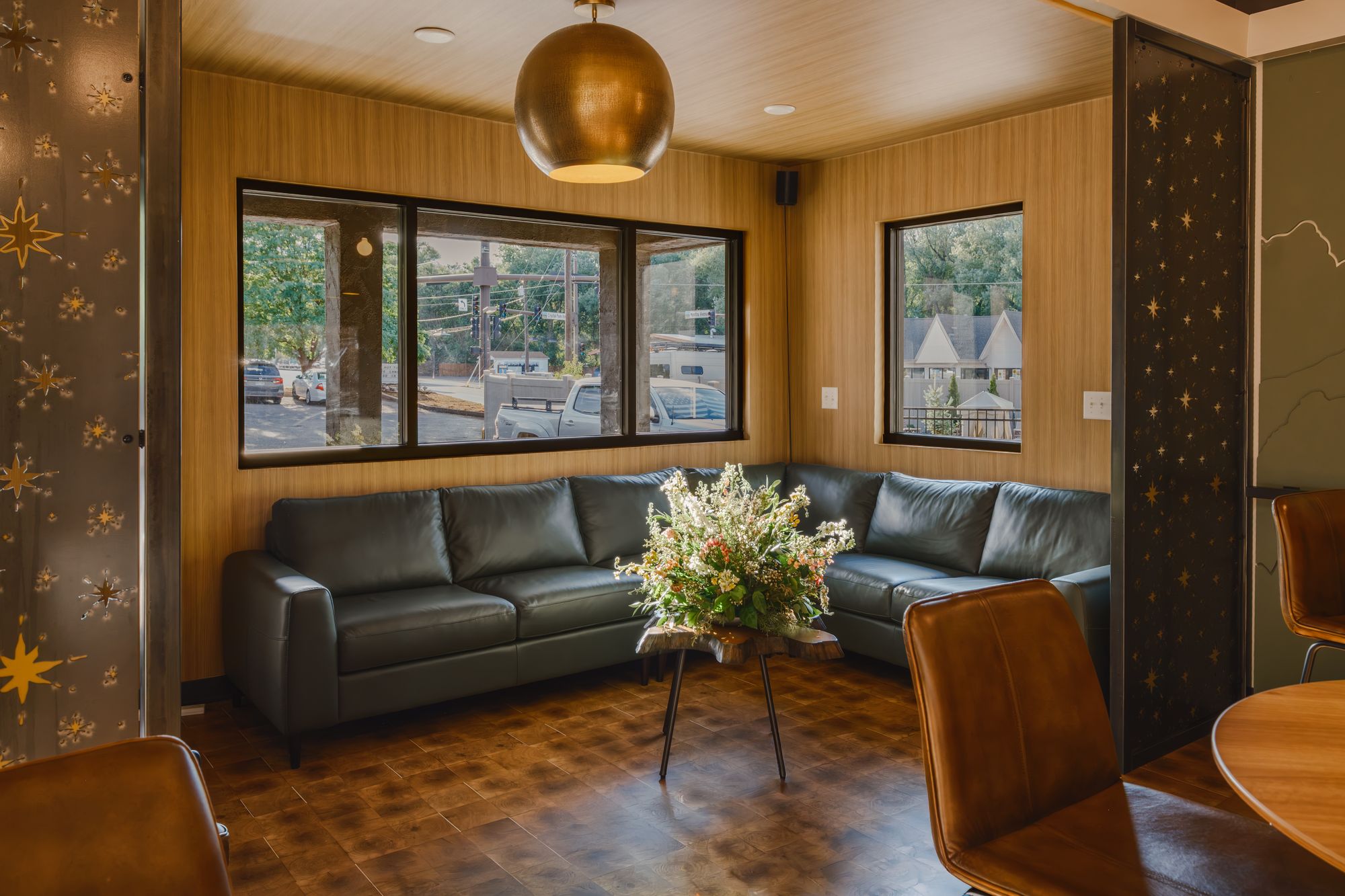 Lobby lounge with black leather sectional, brass pendant, and street-facing windows at The Outrider Hotel