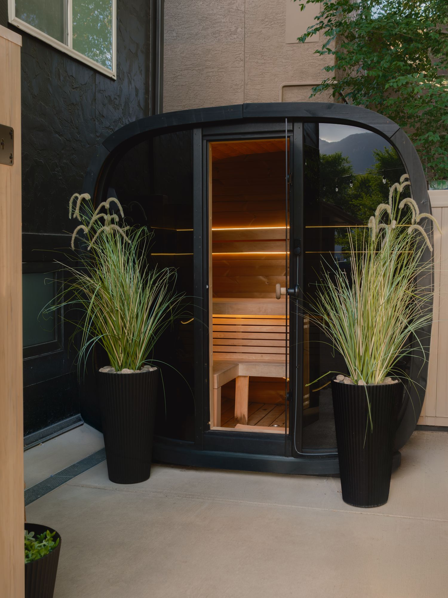 Outdoor Finnish sauna with glass door and ornamental grasses at The Outrider Hotel