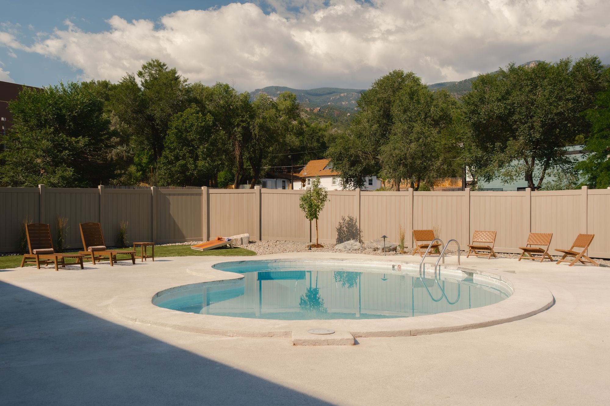 Outdoor pool with lounge chairs and mountain views at The Outrider Hotel in Manitou Springs