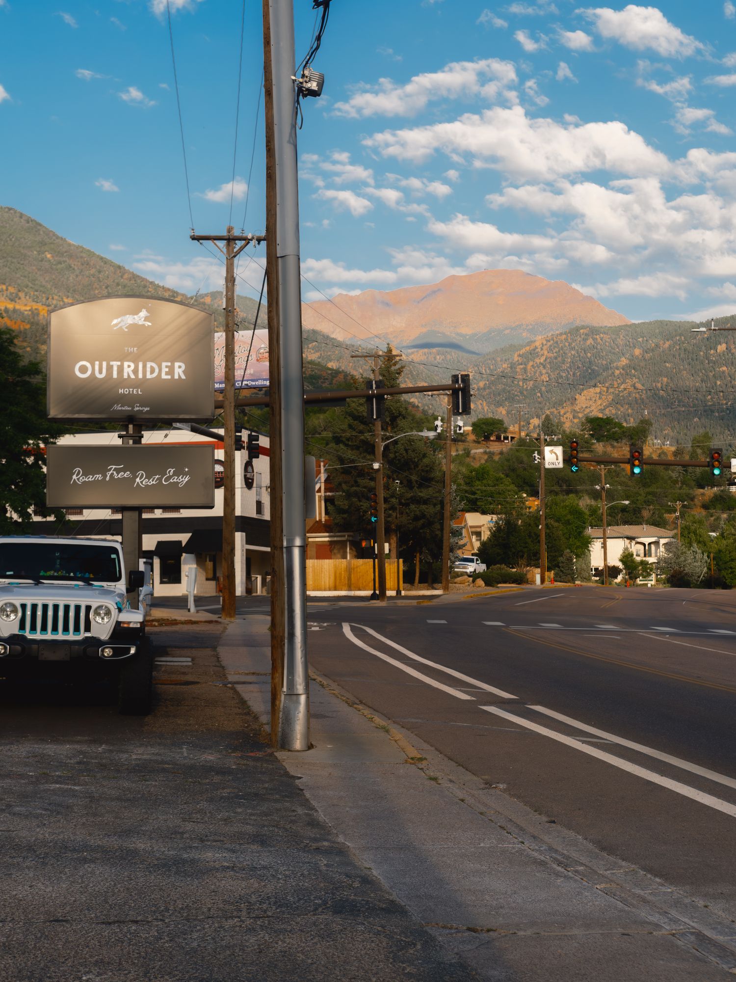 The Outrider Hotel roadside sign on Manitou Avenue with Pikes Peak rising behind it