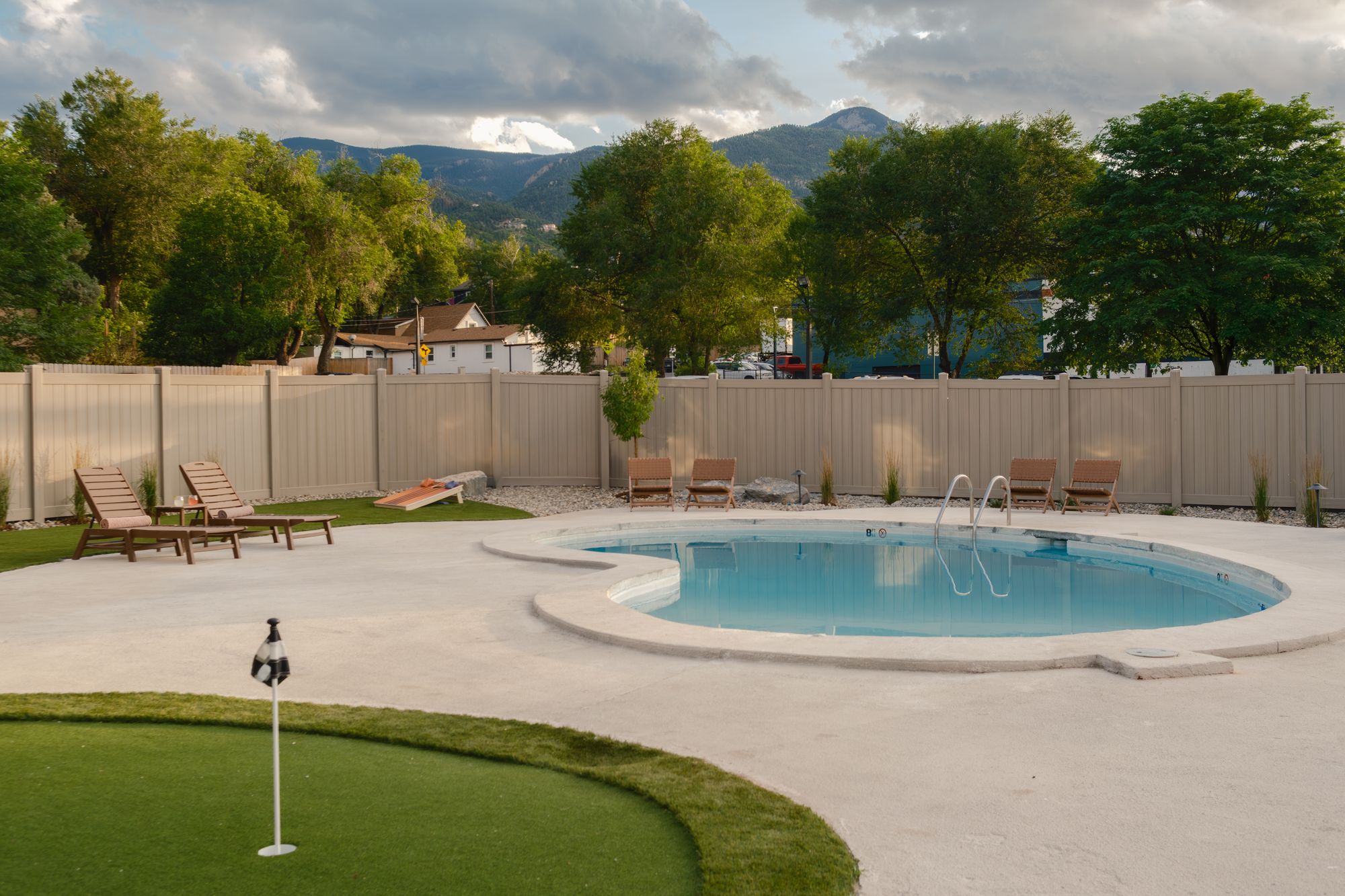 Putting green beside the pool deck with the Manitou Springs foothills beyond at The Outrider Hotel