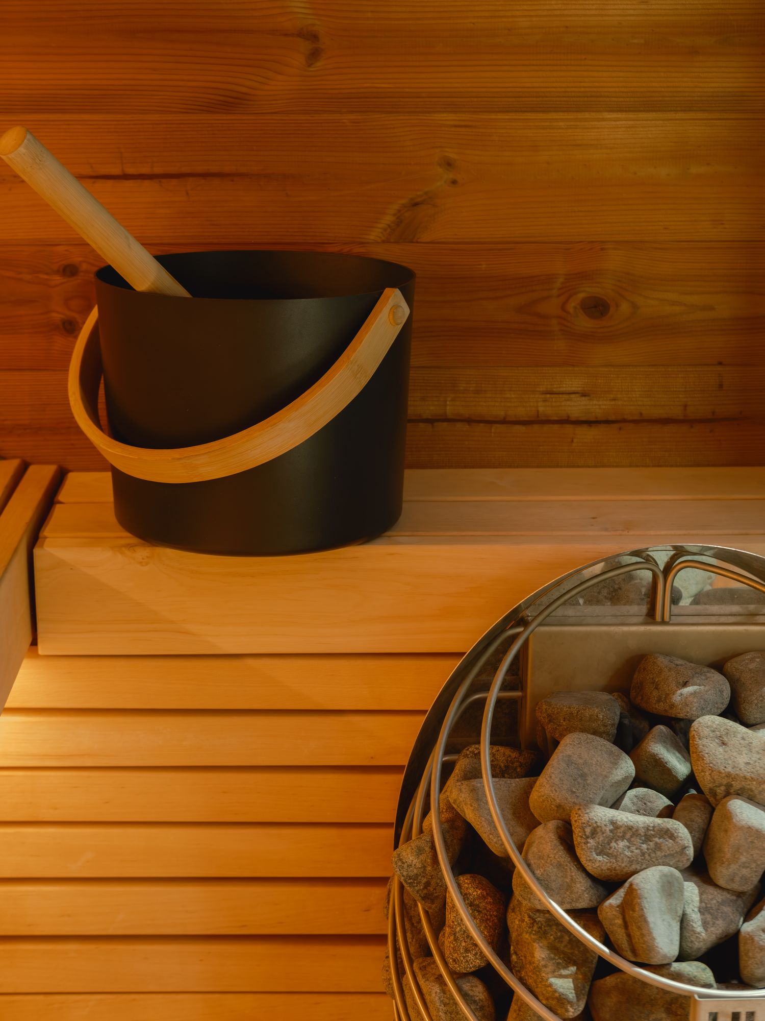 Cedar sauna interior with bucket, ladle, and heated stones at The Outrider Hotel in Manitou Springs